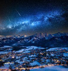Milky way over illuminated Zakopane city after dusk in winter