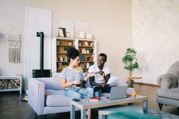 Multiracial people exchanging by credit card in living room