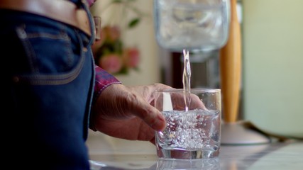 Man pouring water from a clear jug into a water glass