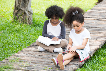 Kids reading a book in summer garden. Children study. Boy and girl play in school yard