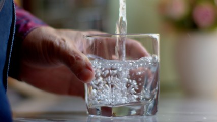 Man pouring water from a clear jug into a water glass