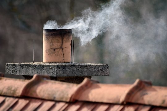 Closeup of smoke coming out of a chimney on the building under the sunlight at daytime
