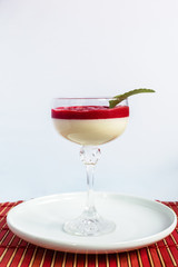 White background panna cotta, with strawberry jam standing on the white plate, with mint leaf