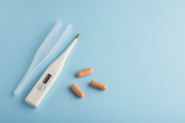 electronic thermometer and tablets on a blue background virus epidemic coronavirus protection