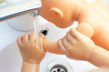child washes his hands a doll. hands in foam of antibacterial soap. Protection against bacteria, coronaviruses. hand hygiene. wash hands with water.