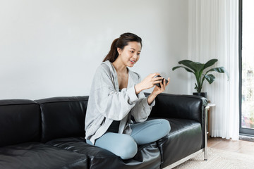 A young Asian woman using mobile phone in the living room