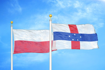 Poland and Netherlands Antilles two flags on flagpoles and blue cloudy sky