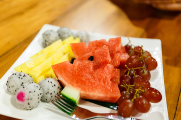 Mixed fruits in white plate for healthy dinner. (Pineapple, watermelon, red grape and dragon fruit)