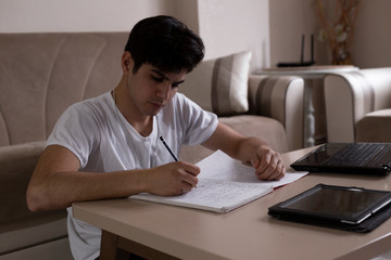 Fototapeta na wymiar Teenage student studying at home using his tablet and computer