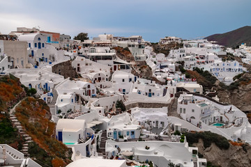 Fototapeta premium Oia town on Santorini island. Old fishing village on hill slope. Romantic honeymoon in beautiful touristic resorts. Amazing white houses on volcanic rocks. Popular landmark in Europe. Greece