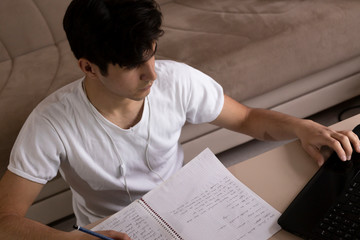 Naklejka premium Teenage student studying at home using his tablet and computer
