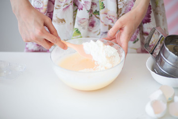 Female hands of a pastry chef whisk cream.Pastry chef whips cream light photo. Pink pastel background.