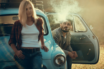 Young couple traveling in a blue vintage car