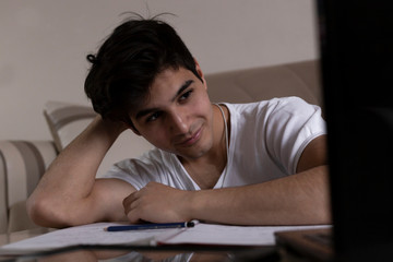 Fototapeta premium Teenage student studying at home using his tablet and computer
