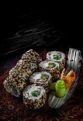 sushi roll with cream cheese, cucumber and eel in plate on black wooden table background
