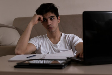 Teenage student studying at home using his tablet and computer