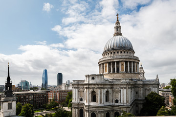 Fototapeta premium Side view of St. Paul’s Cathedral in London against a cloudy sky, with some modern skyscrapers in the background.