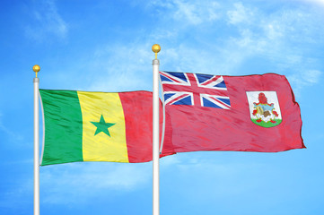 Senegal and Bermuda two flags on flagpoles and blue cloudy sky