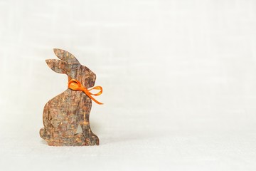 Illustration von Ostern, ein Osterhase aus Holz mit einer orangenen Schleife vor weißem Hintergrund