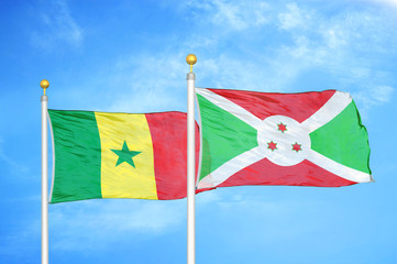 Senegal and Burundi  two flags on flagpoles and blue cloudy sky