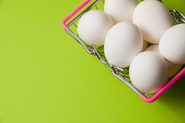 Eggs in a metal grocery basket on a neon green background