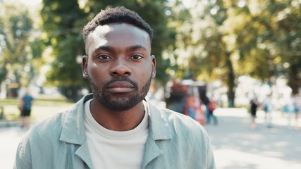 Portrait of handsome young african american stylish man looks at the camera in the city street sunlight sunse face outside black summer