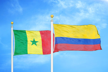 Senegal and Colombia two flags on flagpoles and blue cloudy sky