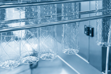 The PET bottles hanging on  the rail on the conveyor belt for filling process in the drinking water factory. The drinking water factory production process by automatic filling machine in the plant.