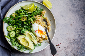Quinoa salad with egg and avocado in gray bowl, gray background, top view. Paleo diet menu concept.