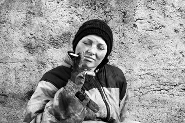 Homeless dirty woman with a cigarette in her hands