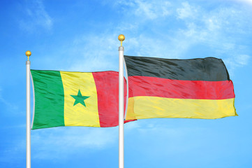 Senegal and Germany two flags on flagpoles and blue cloudy sky