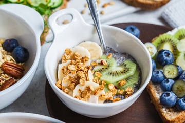 Chia pudding with granola, kiwi and banana in a white bowl. Vegan breakfast concept.