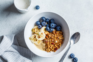 Granola with berries and fruits in a white bowl on a gray background. Healthy breakfast concept.