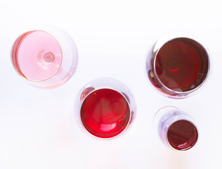 Four glasses of wine: red and pink on white background with sparkling shadows. Top view. Free copy space.  Concept of organic drinks.