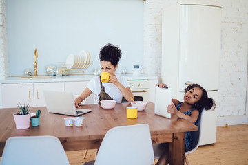 Mother and daughter using gadgets in kitchen
