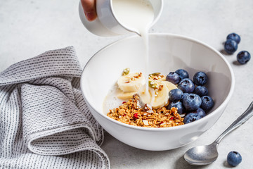 Granola with milk, berries and fruits in a white bowl. Healthy breakfast concept.