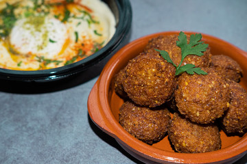 Homemade falafel in a clay bowl with hummus in background. Close up view.