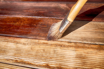 brush covers the wooden plank surface with a stain side view close up
