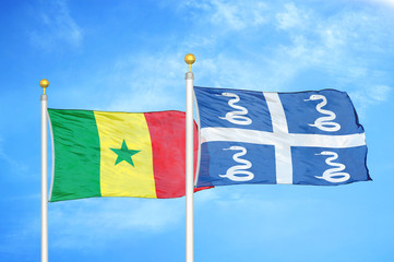 Fototapeta premium Senegal and Martinique snake two flags on flagpoles and blue cloudy sky