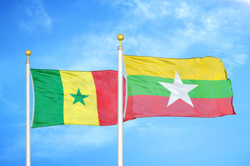 Senegal and Myanmar two flags on flagpoles and blue cloudy sky