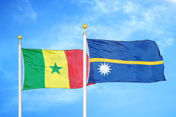 Senegal and Nauru two flags on flagpoles and blue cloudy sky