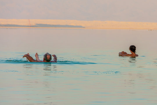 People Enjoying The Dead Sea At Golden Hour