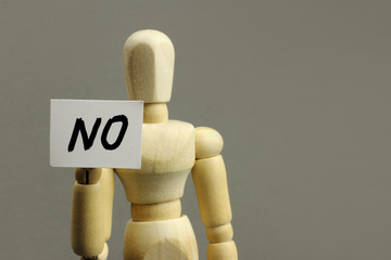 A wooden figure holding the inscription NO, concept