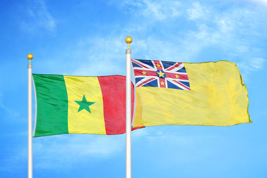 Senegal and Niue two flags on flagpoles and blue cloudy sky