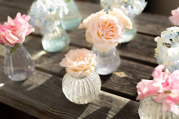 Decoration of blooming blue hydrangea, sweet pea Lathyrus, bush roses in small crystal vases on wooden background. Design,creative.International Women's Day,March 8 and Valentine's Day,14 of February
