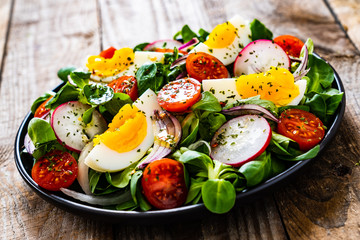 Salad with boiled egg and vegetables on wooden table
