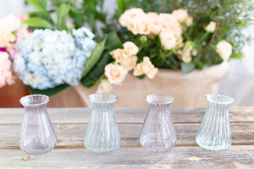Small crystal vases on a wooden background in rustic style.Blue hydrangea, tea roses, greenery, home garden. Greetings for International Women's Day holiday on March 8,Valentine's Day, 14 of February