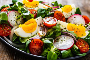 Salad with boiled egg and vegetables on wooden table
