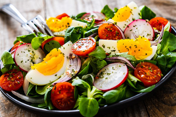 Salad with boiled egg and vegetables on wooden table
