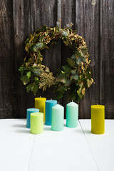 candles on table, dried ivy wreath on old wooden wall